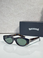 Cat-eye glasses with dark frame, tinted green lenses, and gold-toned metal details