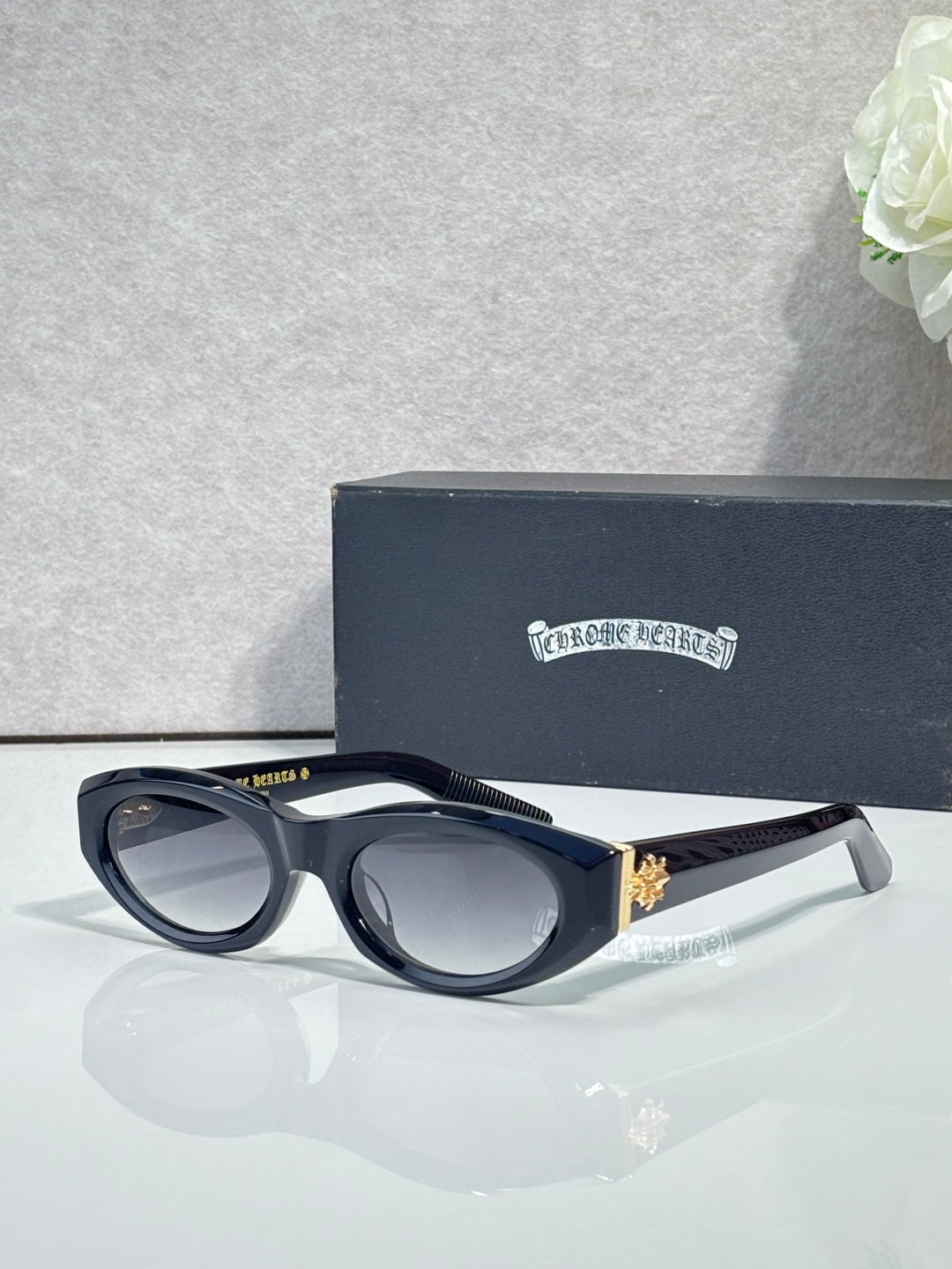 Cat-eye glasses side view with dark frame, tinted lenses, and gold-toned emblem detail