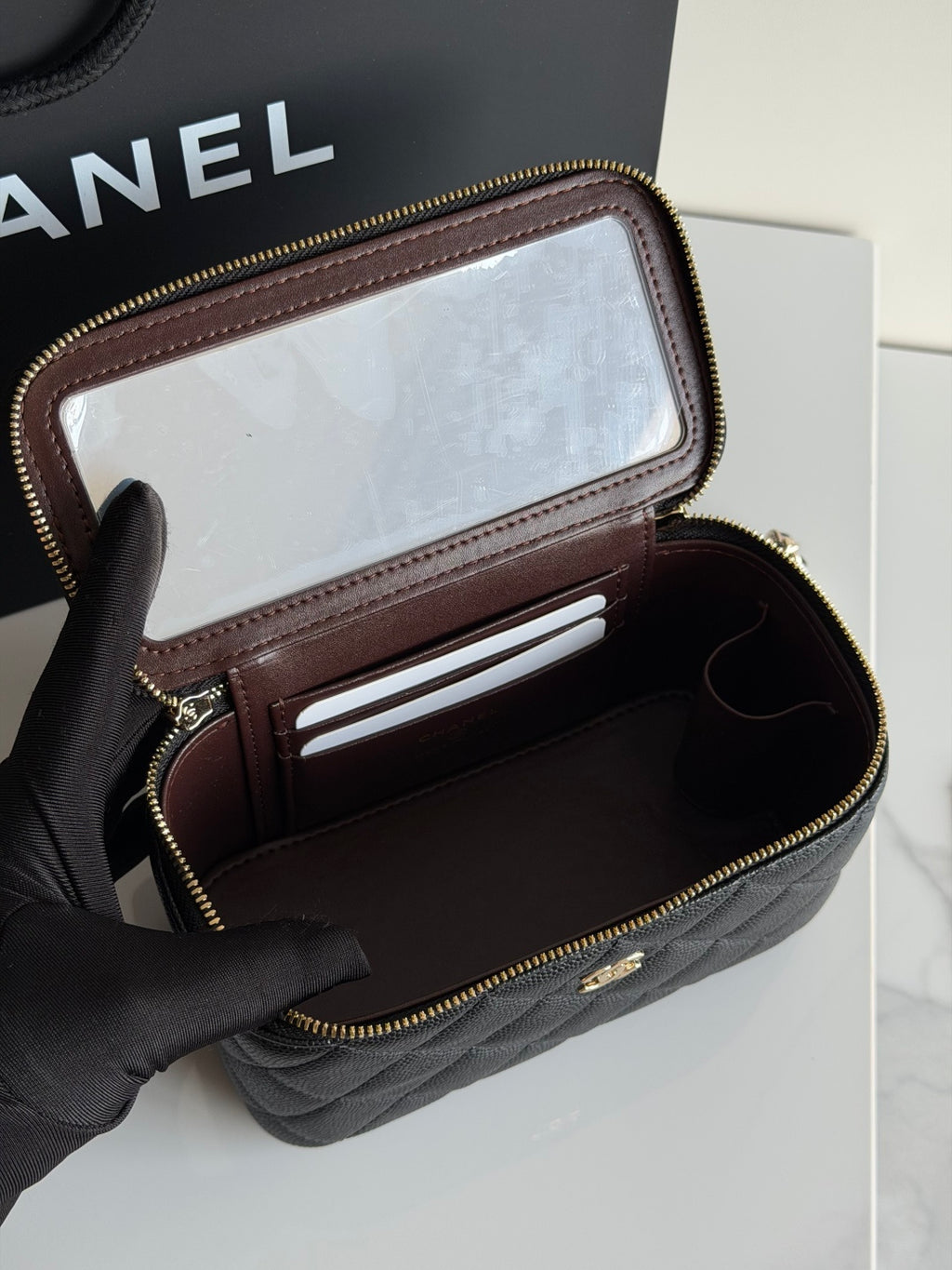 Quilted shoulder bag in black leather with flap open, showing card slot and interior pockets.