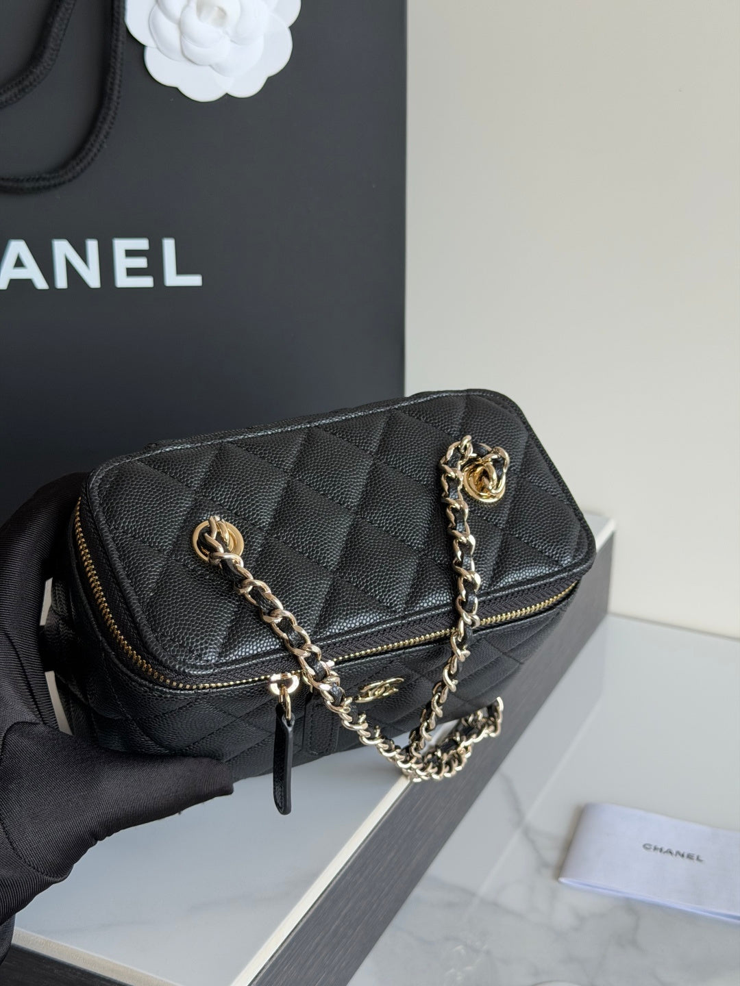 Quilted shoulder bag in black leather with gold zipper, chain strap, and CC emblem.