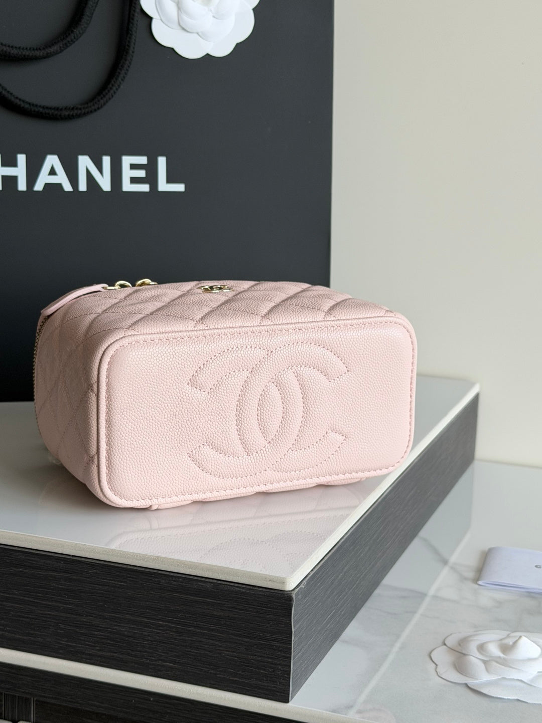 Pink quilted vanity bag with CC logo on front, gold zip and rounded top.