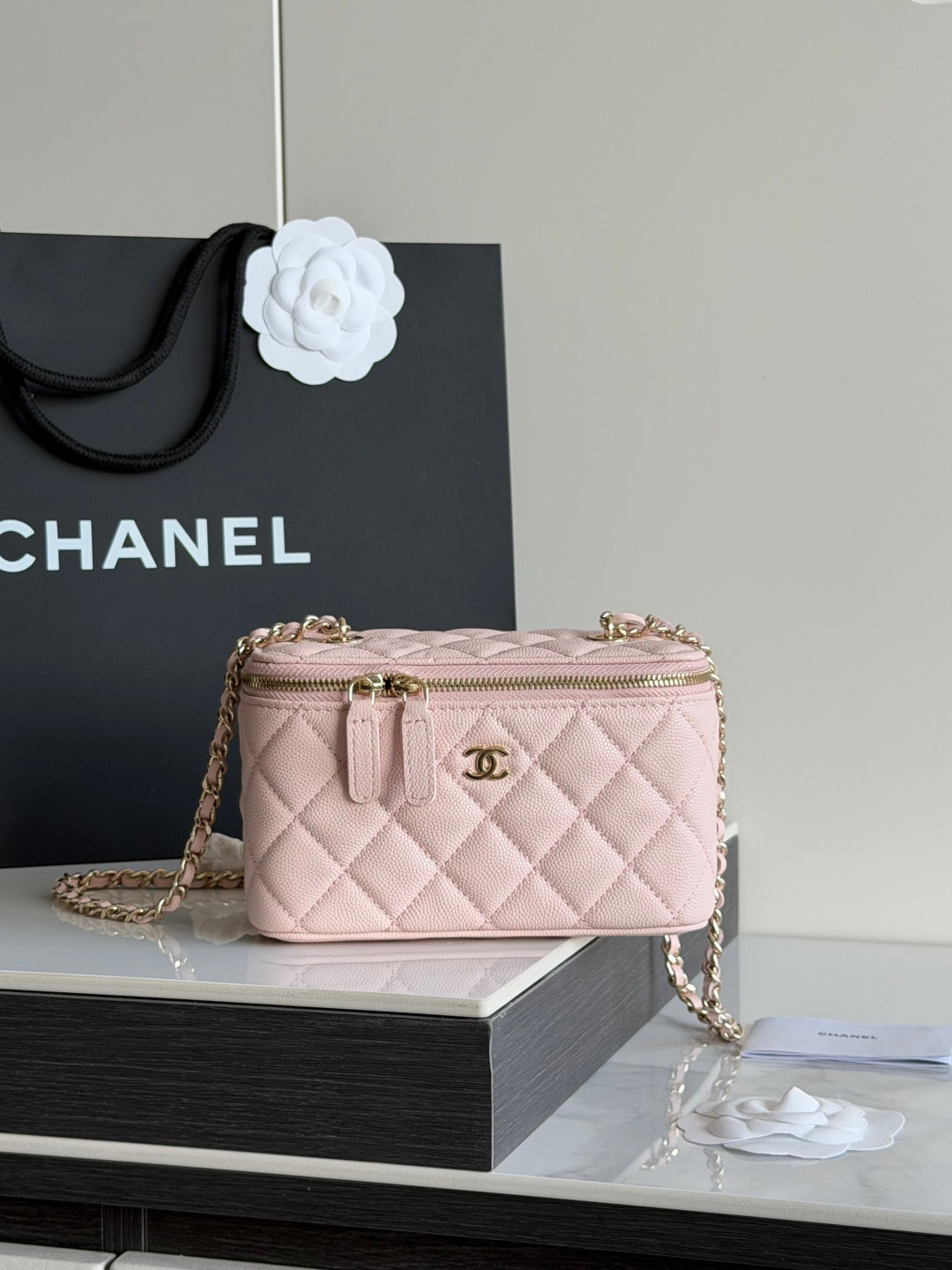 Quilted mini shoulder bag in pale pink with gold chain and top zip closure.