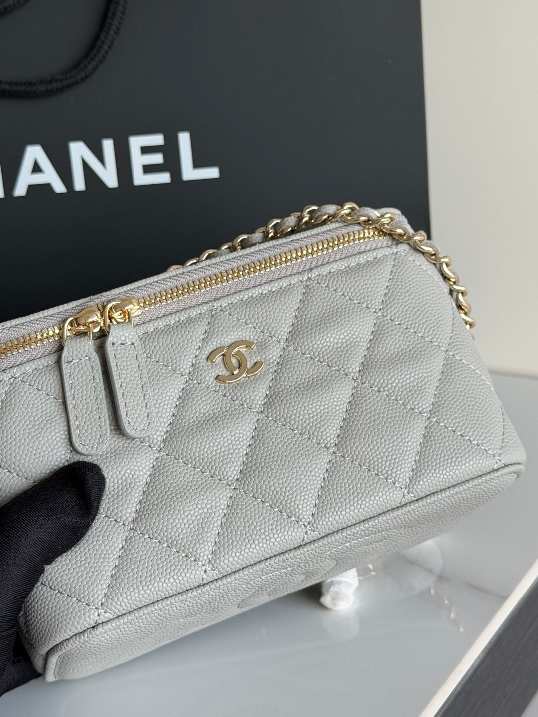 Quilted Chanel mini handbag with gold-tone zipper and CC logo on front.