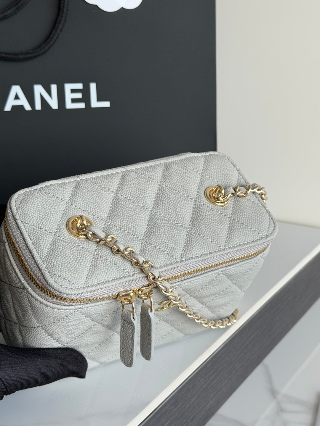 Mini quilted Chanel handbag with gold CC emblem, front zipper, and chain strap.