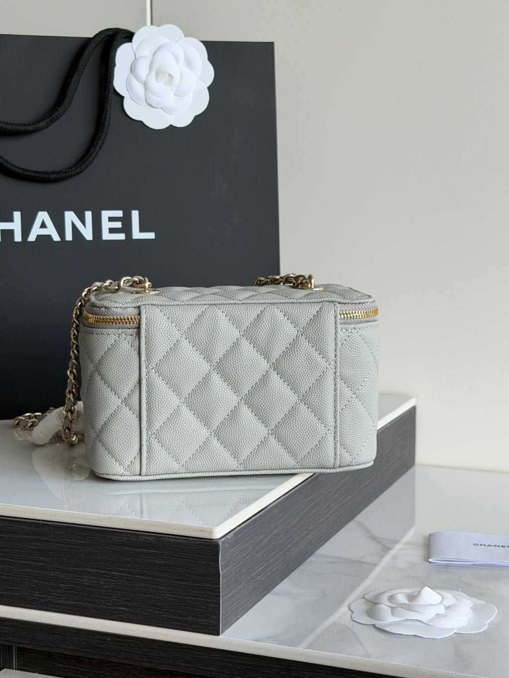 Small quilted Chanel handbag with gold top zipper and short handle detail.