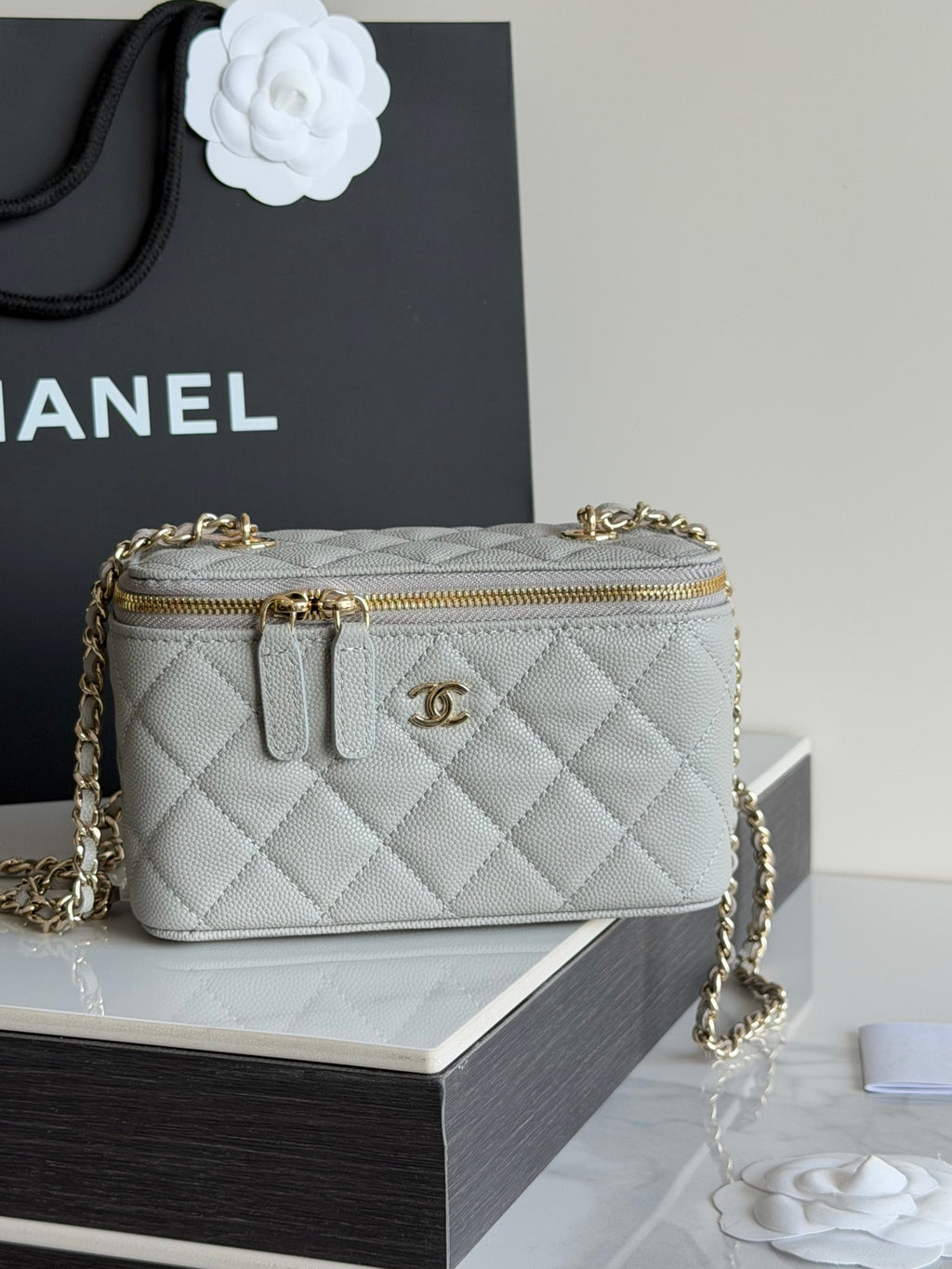 Small quilted Chanel handbag with gold chain shoulder strap and top zip.