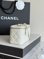 White quilted Chanel mini bag with gold clasp hardware, chain strap, and top zip