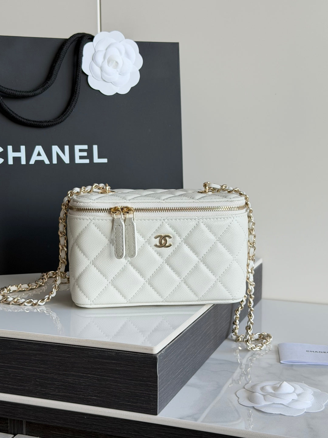 White quilted Chanel mini crossbody bag with gold chain and top zip opening