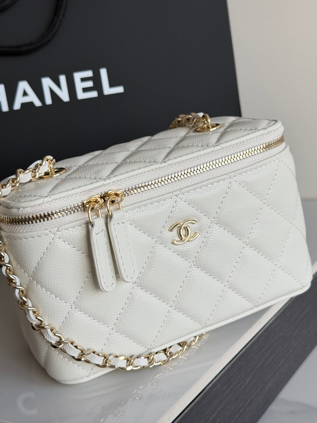 White Chanel quilted mini bag close-up with gold chain strap and top zipper