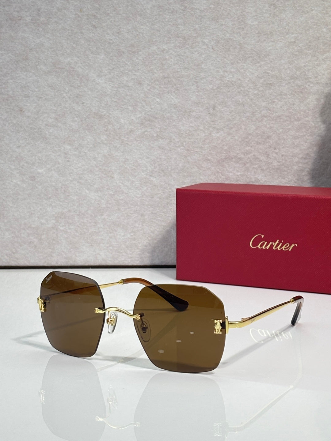 Gold-framed sunglasses with brown-tinted lenses and angular shield shape