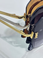 Sunglasses close-up: gold temple hinge with dark lens and glossy metal frame