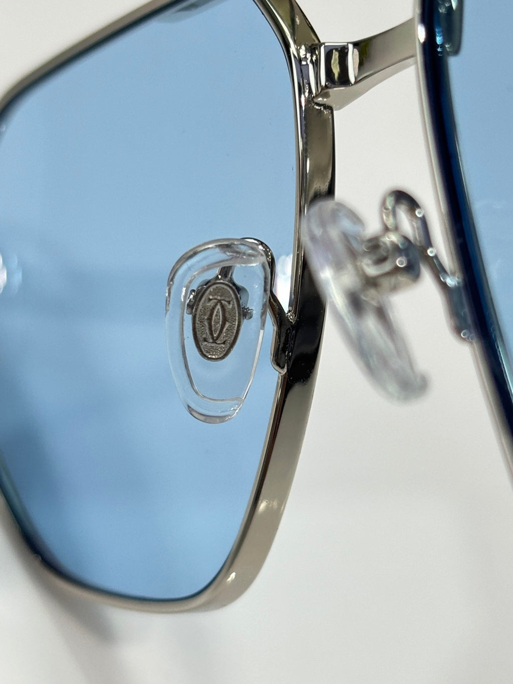 Cartier sunglasses close-up of blue lens and metal frame hinge