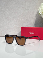Black square sunglasses with brown-tinted lenses and Prada logo on temples