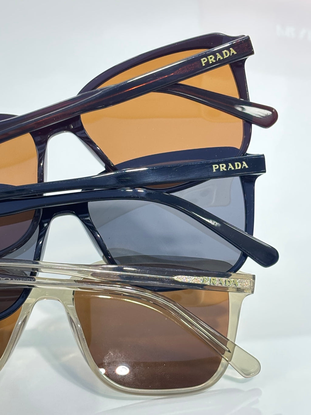 Stacked sunglasses with navy frames and amber-tinted lenses, Prada logo on temple