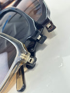 Close-up of dark sunglasses frame with metal hinge detail and Prada logo temple