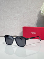 Black square sunglasses with dark lenses and Prada logo on temples