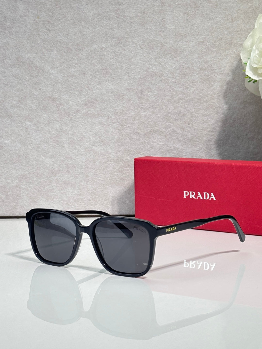 Black square sunglasses with dark lenses and Prada logo on temples