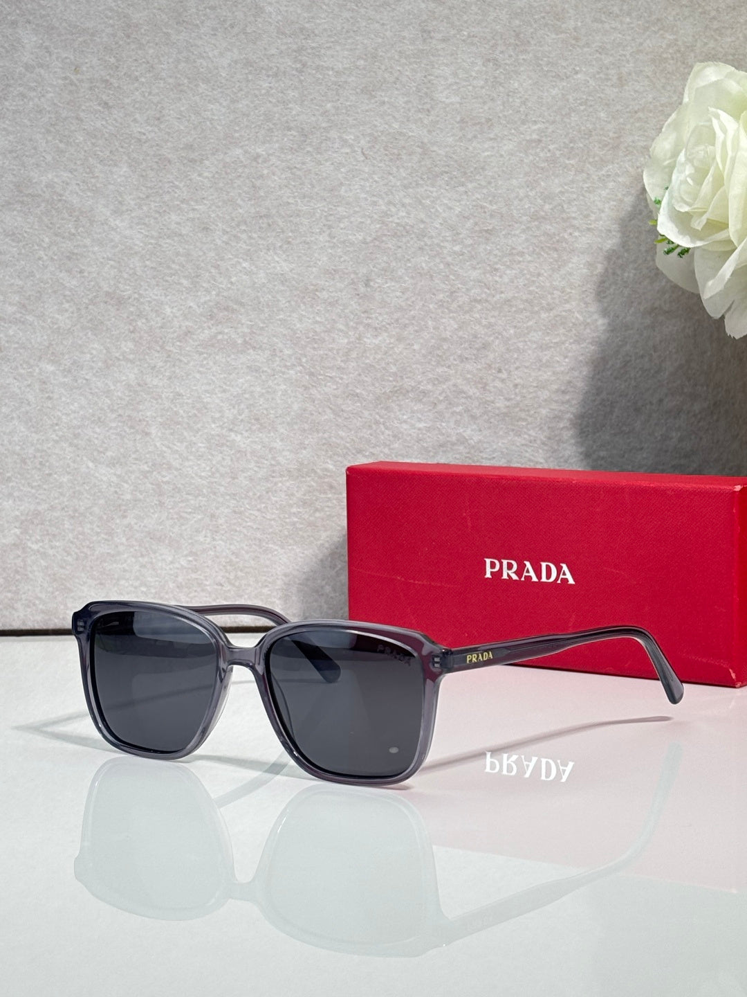 Black square sunglasses with dark lenses and Prada logo on temple