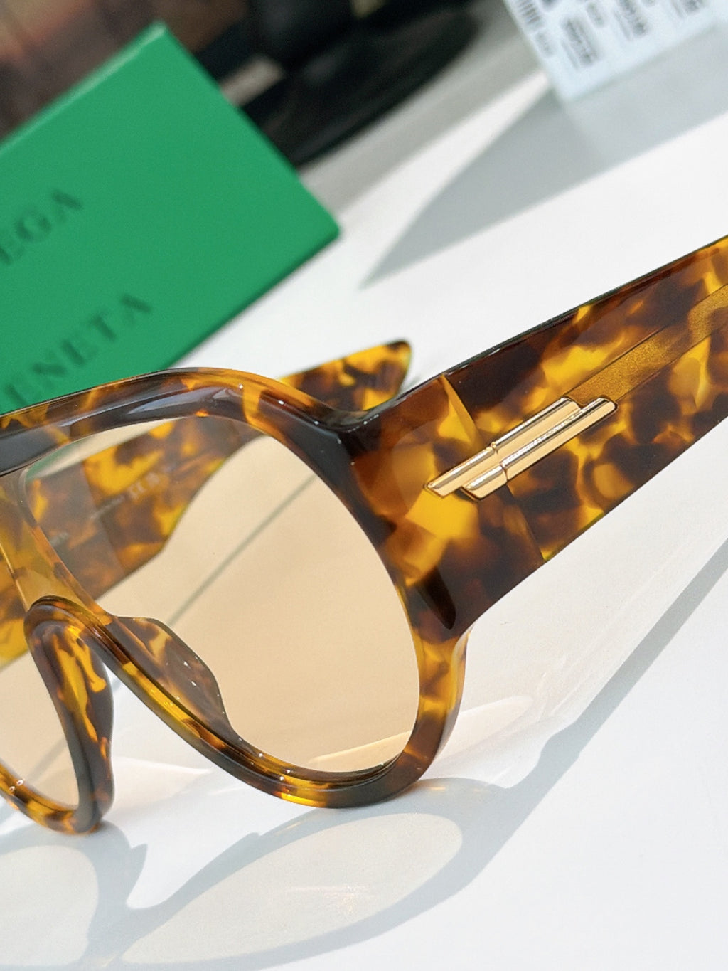 Bottega Veneta sunglasses close-up: tortoiseshell frame, round lens, gold temple bar