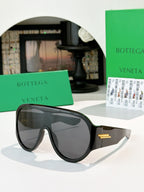 Bottega Veneta sunglasses with dark lenses and black frames, gold temple bar