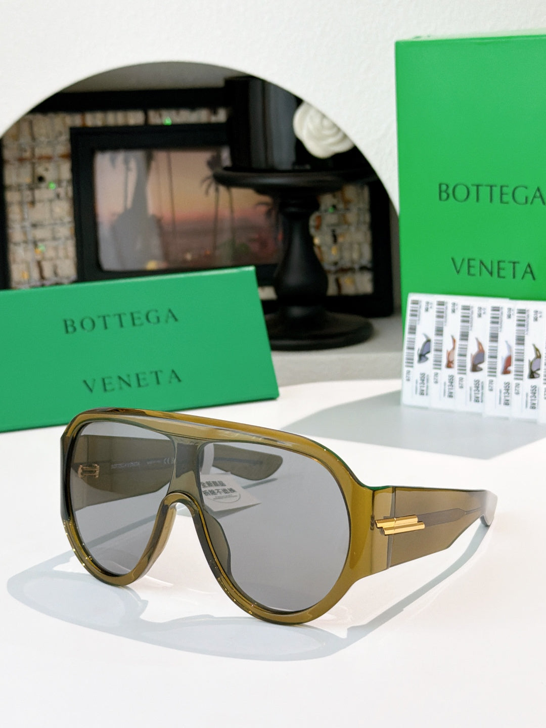 Bottega Veneta sunglasses with light gray lenses and olive tortoiseshell frames, gold hinge