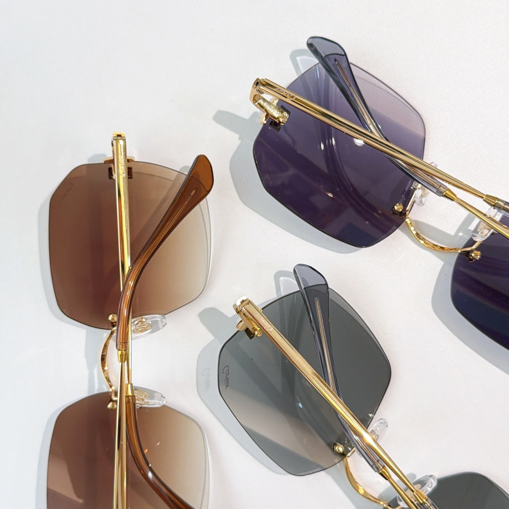 Assorted Cartier sunglasses with mixed tinted lenses and gold frames, overlapping