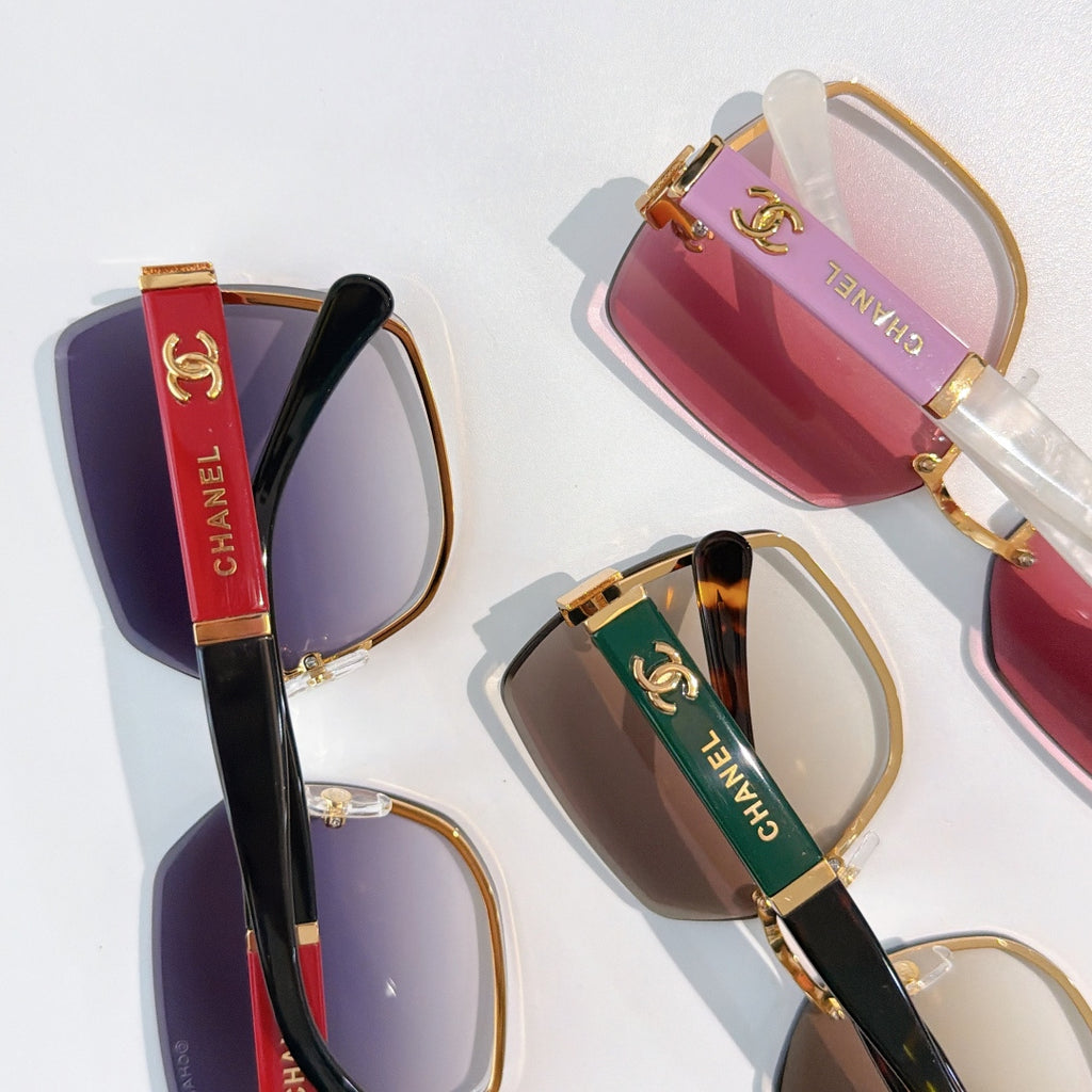 Close-up of sunglasses with purple, red, and brown gradient lenses and gold hardware