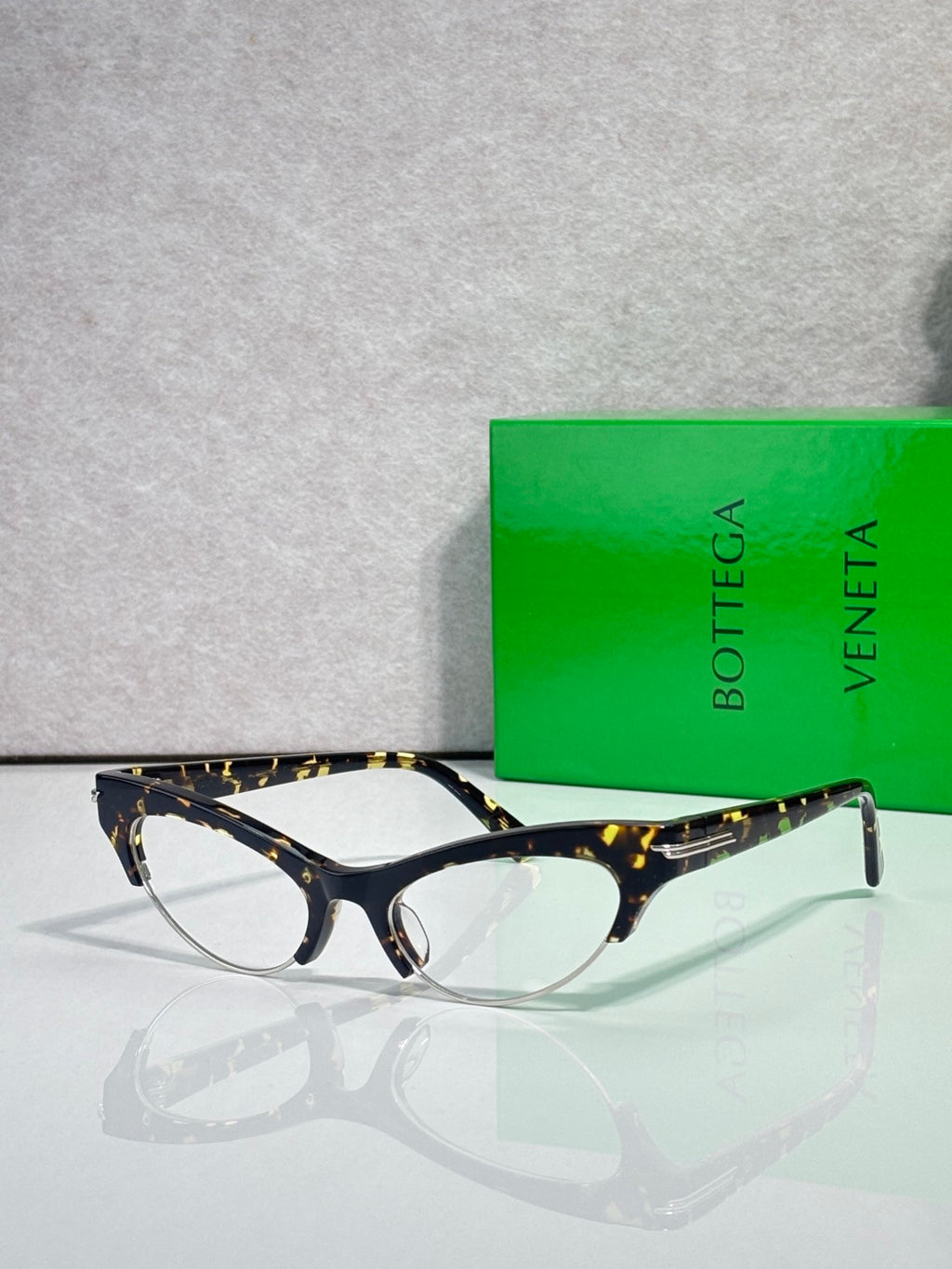 Bottega Veneta glasses with tortoiseshell front, dark temples, and clear lenses