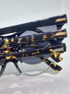 Bottega Veneta glasses close-up: dark tortoiseshell temples with gold bars, clear lens