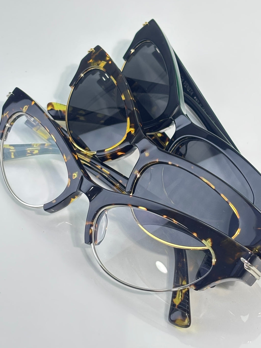 Eyeglasses pair with navy frames, tortoise detailing, gold hinges, and tinted lenses.