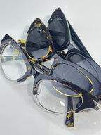 Eyeglasses pair with navy frames, tortoise detailing, gold hinges, and tinted lenses.