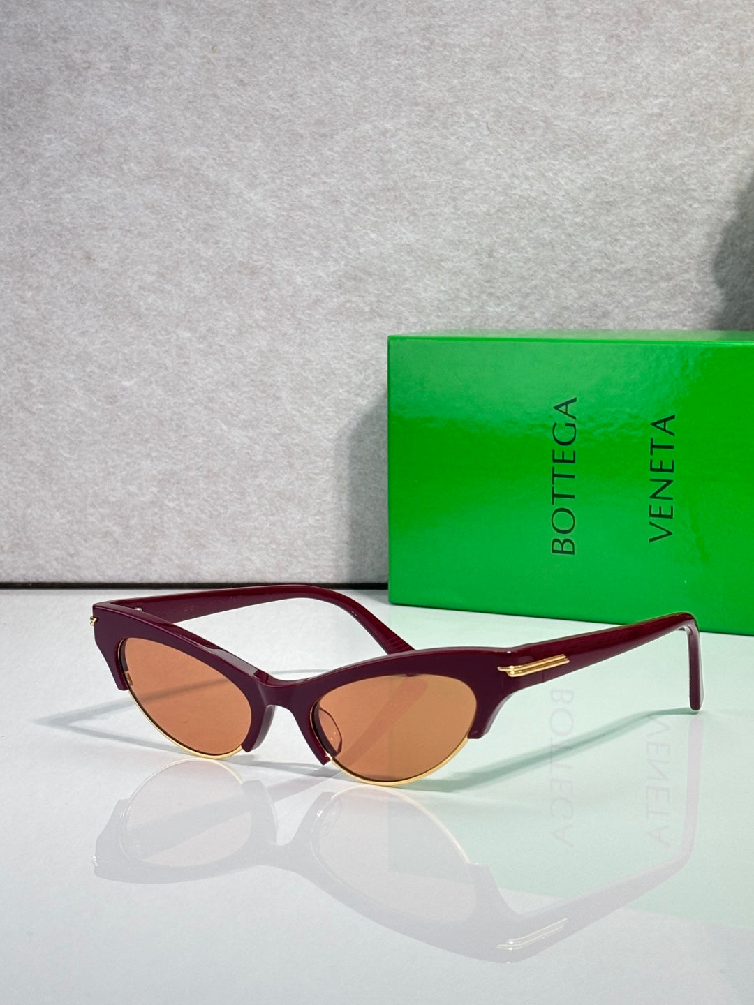 Eyeglasses with burgundy frame, brown tinted lenses, and gold metal bridge.