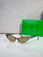 Eyeglasses with olive-toned frame, light brown lenses, and gold hinge details.
