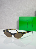 Bottega Veneta eyeglasses with dark lenses, tortoise temples, and gold accents.