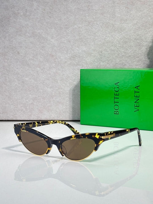 Bottega Veneta eyeglasses with dark lenses, tortoise temples, and gold accents.