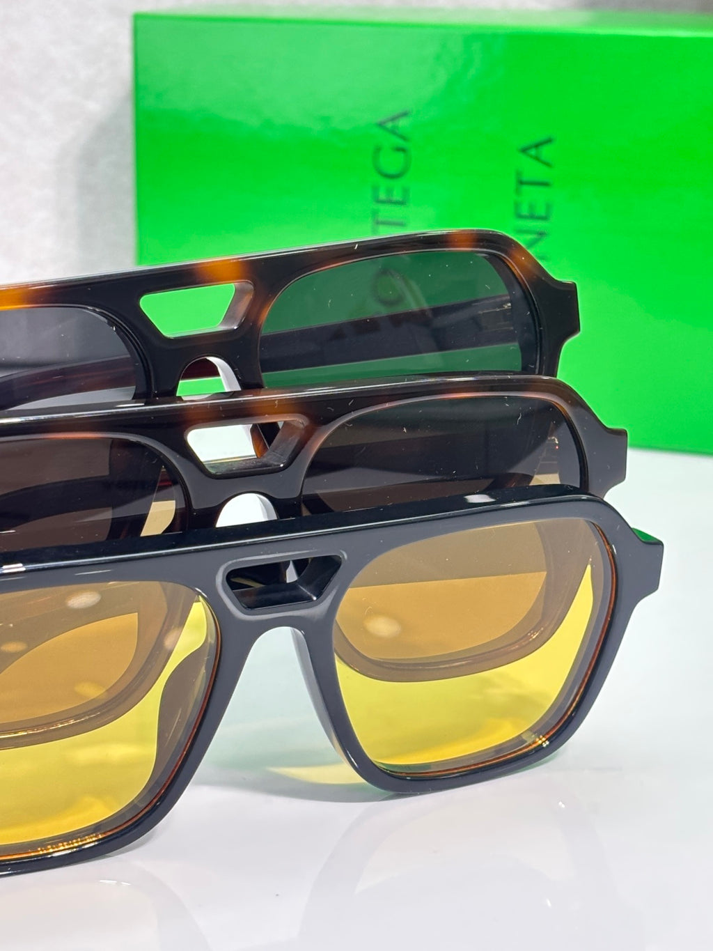 Stacked dark and tortoiseshell eyeglass frames with yellow lenses