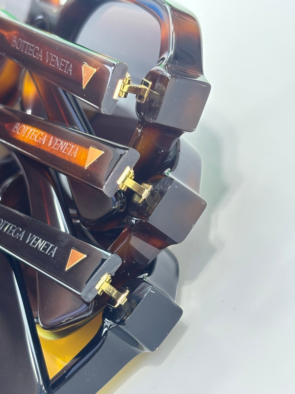 Sunglasses temples detail with brand etching and gold-tone hinges, close-up