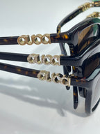 Gucci sunglasses detail: gold logo embellishments on navy temple