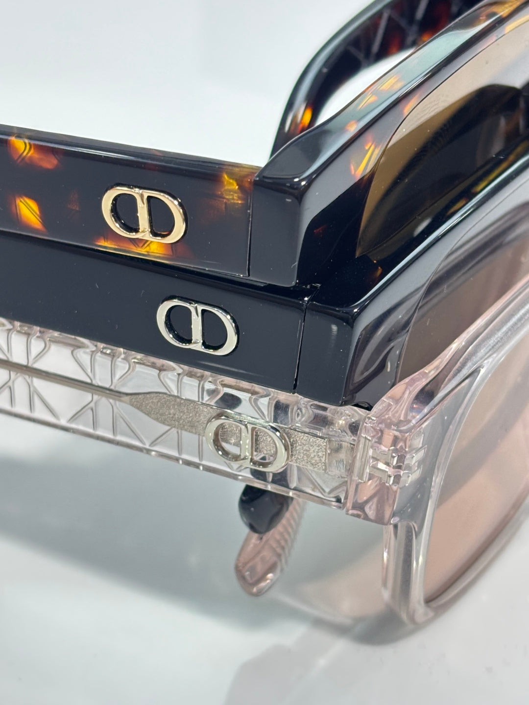 Clear sunglasses with metal logo on temples and dark tinted lens