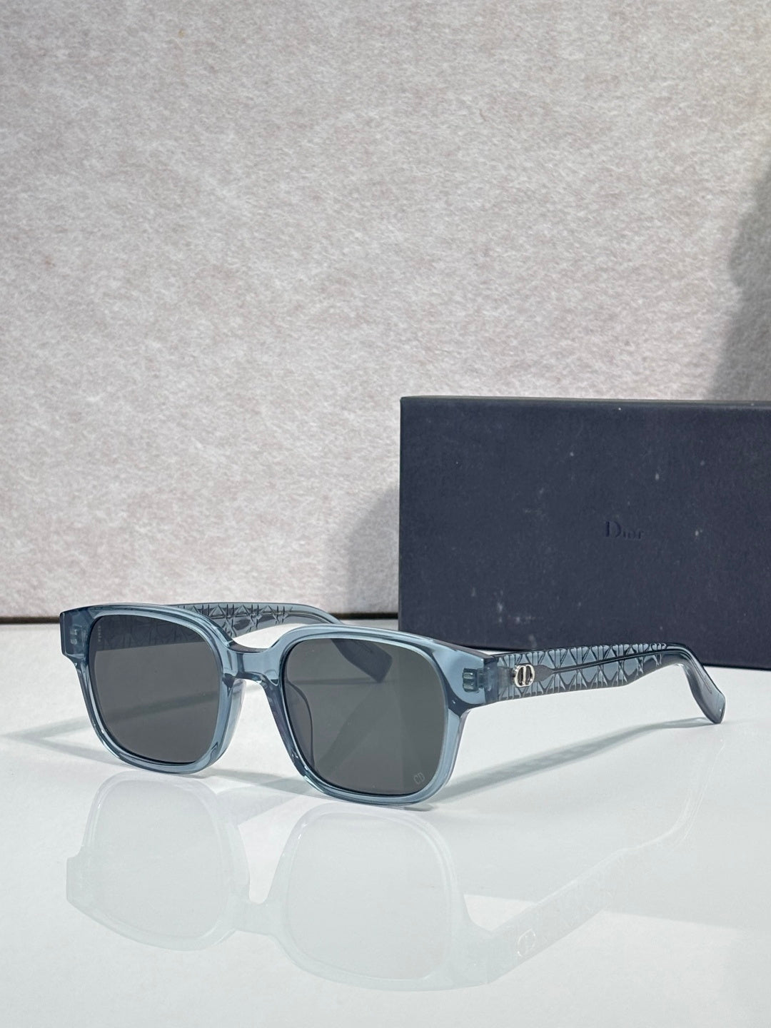 Blue sunglasses with dark lenses and patterned temple detailing