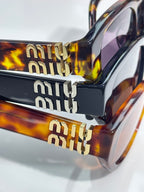 MiuMiu eyeglasses close-up of tortoiseshell temple and gold-tone logo detail