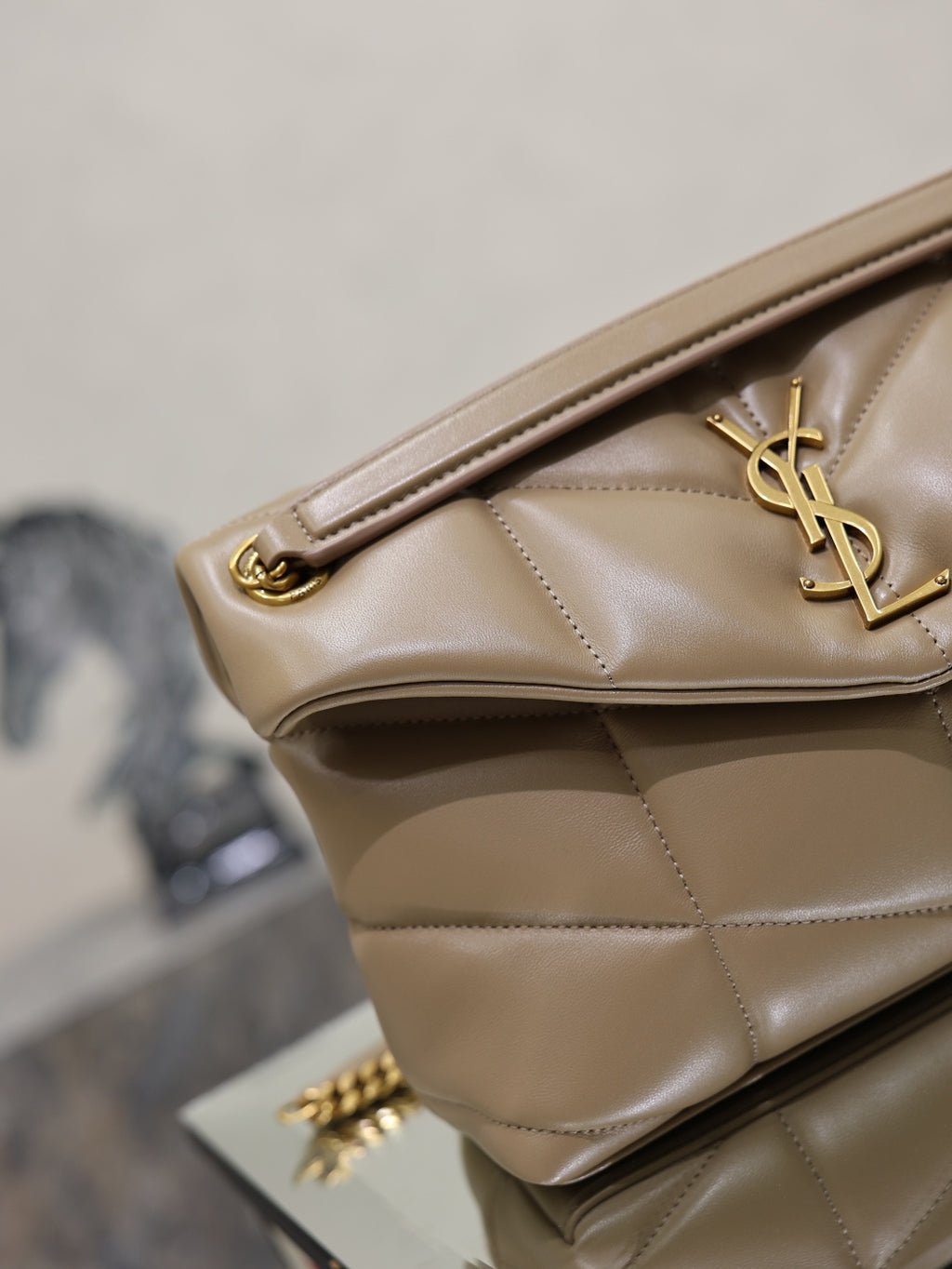 YSL beige quilted bag close-up with gold hardware and YSL logo