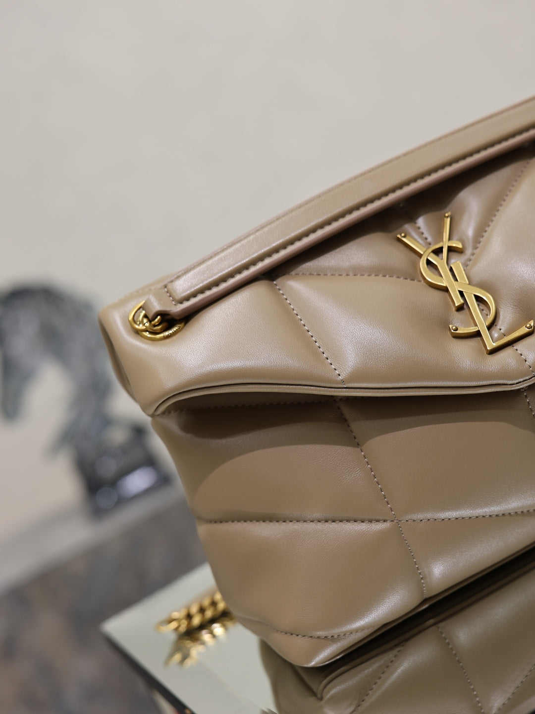 YSL beige quilted bag close-up with gold hardware and YSL logo