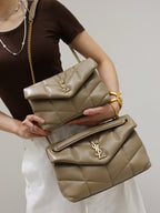 YSL quilted shoulder bag with flap and gold YSL logo, carried in hand, beige