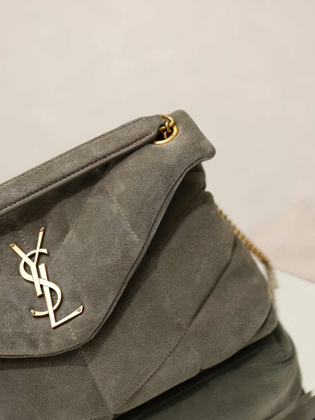Gray YSL shoulder bag flap detail with gold YSL logo, on quilted front
