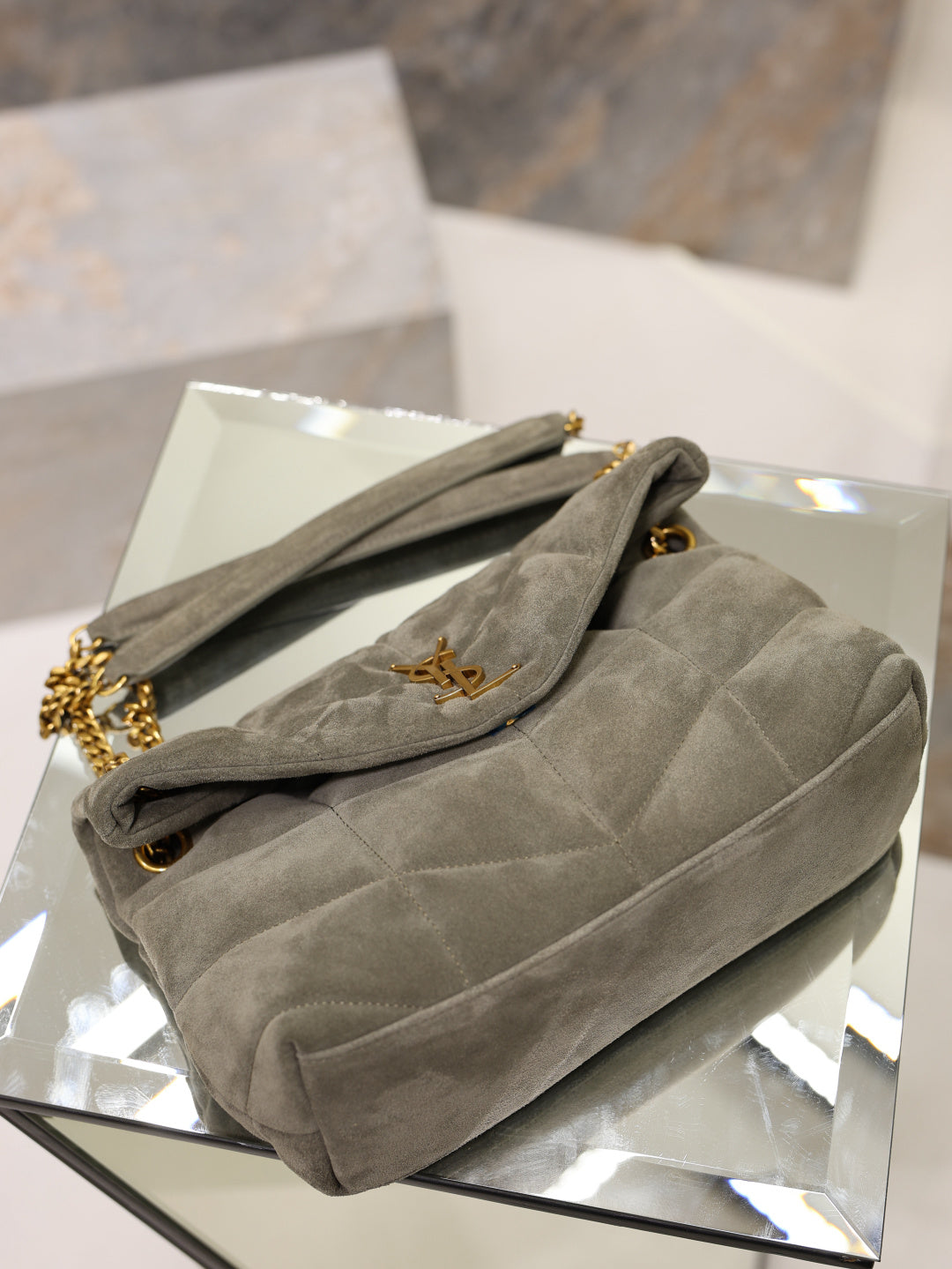Gray YSL quilted shoulder bag with gold chain strap and flap logo on display