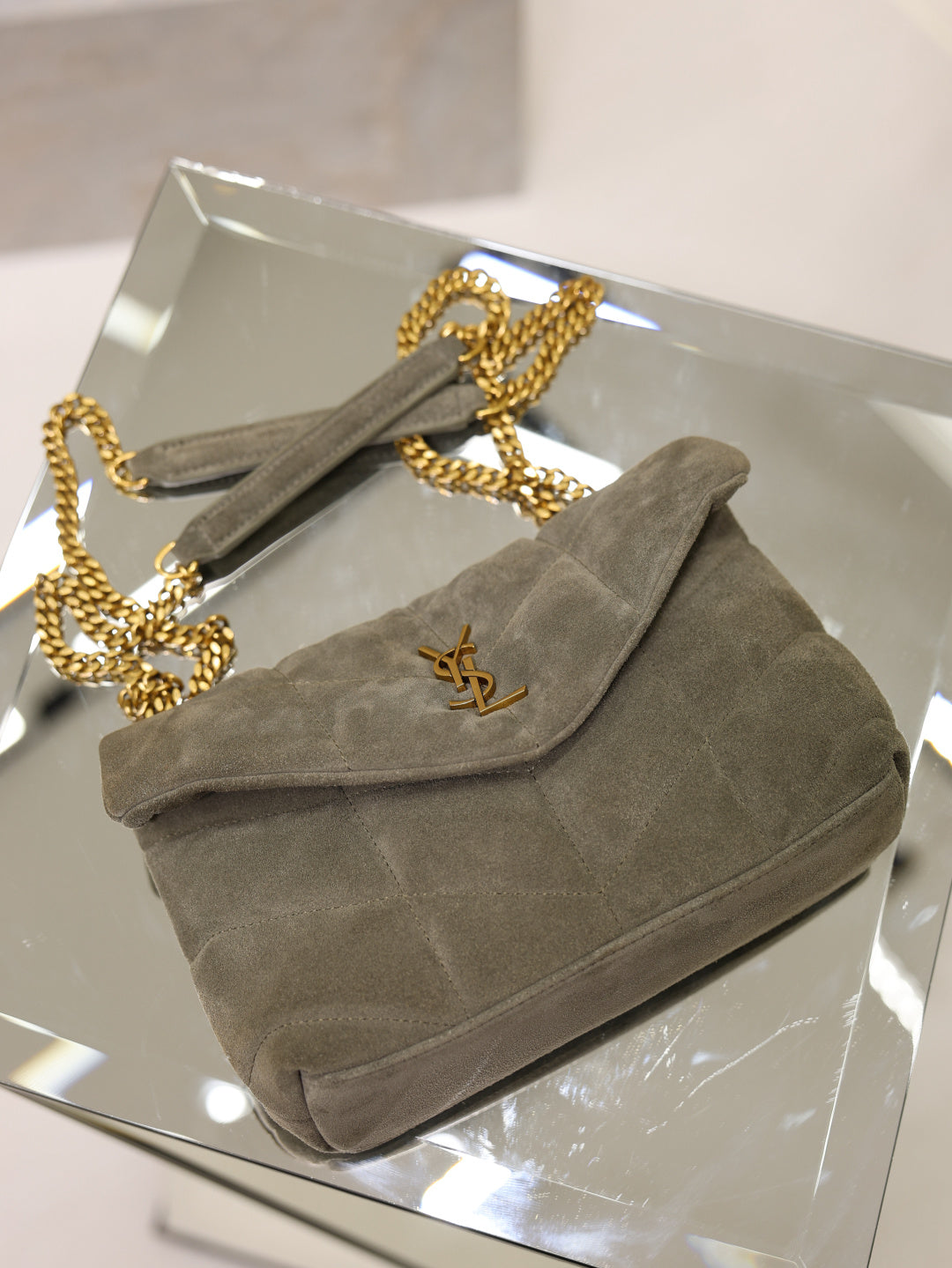 Gray suede shoulder bag with flap, gold YSL logo, and chain shoulder strap