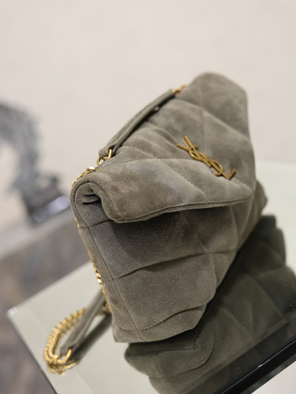 Gray suede shoulder bag with quilted sides, gold chain strap, clasp hardware