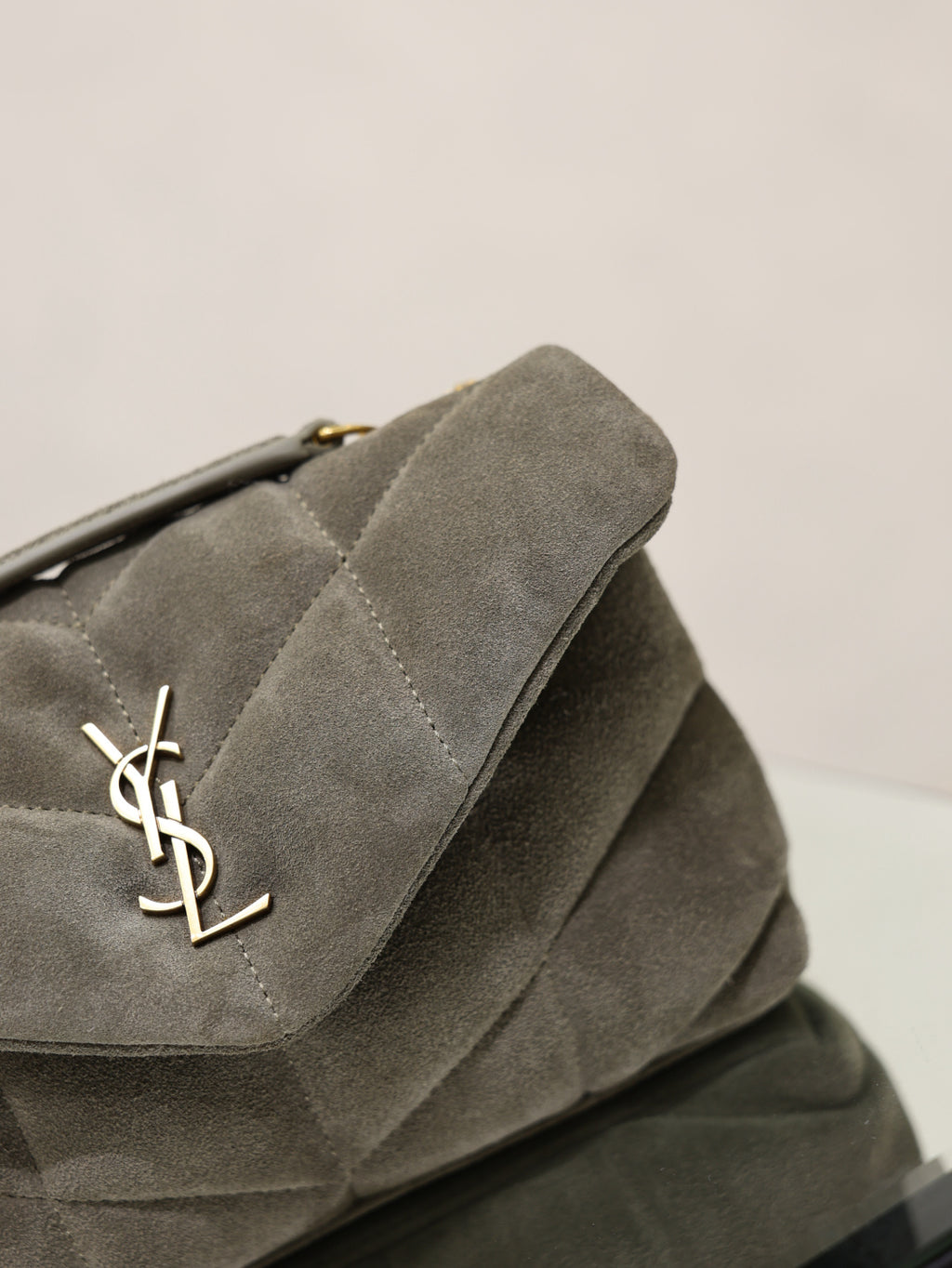 Gray suede shoulder bag flap with gold YSL logo and stitched edge detail