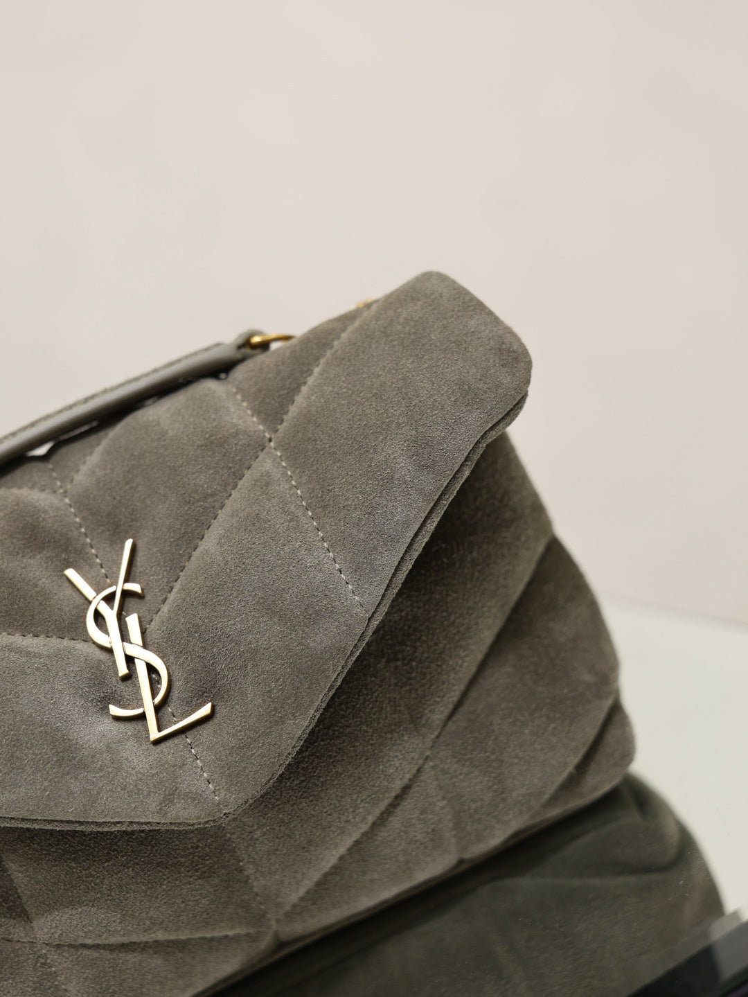 Gray suede shoulder bag flap with gold YSL logo and stitched edge detail
